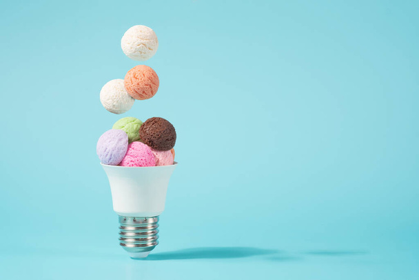 Ice cream balls falling into the light bulb cone. Electricity shortage minimal concept. - Photo, Image