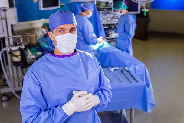 Kaukázusi férfi orvosi ellátás frontvonali orvosának portréja kórházi PPE steril arctisztító kesztyű a beteg intenzív osztályán - Fotó, kép