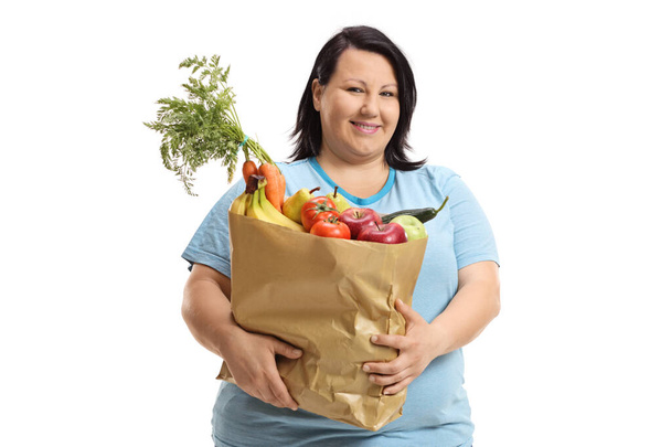 Young woman holding a paper bag with fruits and vegetables isolated on white background - Fotoğraf, Görsel