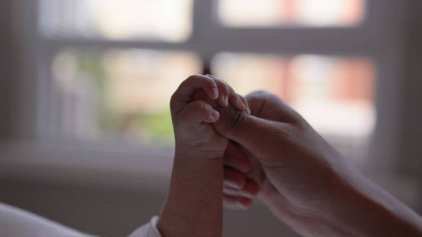 Cute baby in white holding mothers hand and sucks his thumb. Happy motherhood concept - Photo, Image