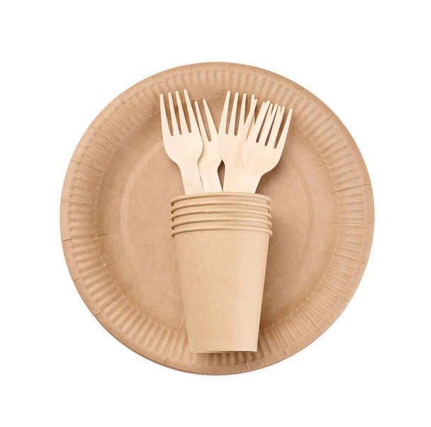 Copas de papel marrón, tenedor de madera y platos sobre un fondo blanco. Basura reciclable, rechazo de plástico, vista superior - Foto, imagen