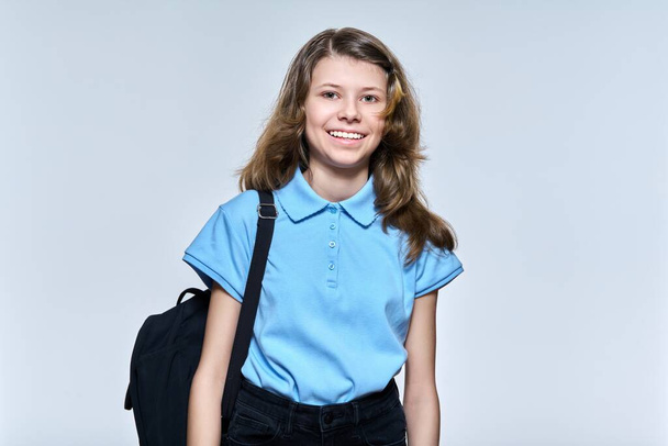 Portrait of schoolgirl 11, 12 years old with backpack, girl looking at camera on light studio background - Foto, imagen