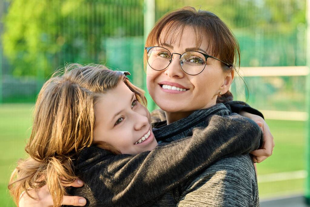 Portrait of happy mom and preteen daughter hugging together outdoor - Foto, immagini