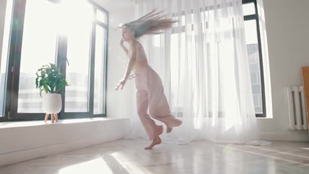 Baile callejero - joven mujer delgada baila en habitación espaciosa blanca a la luz del día - Metraje, vídeo