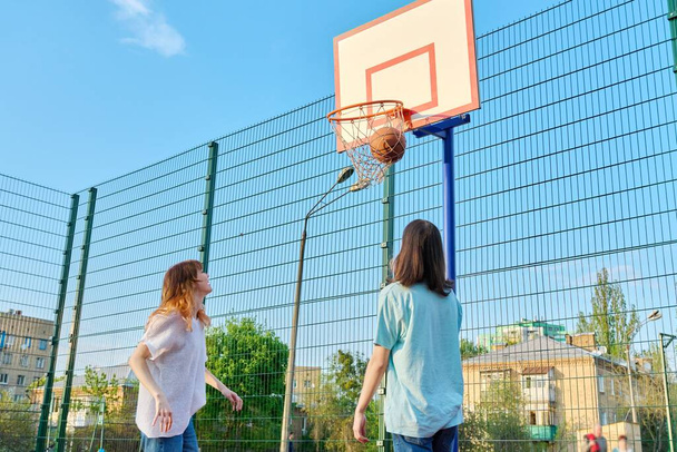 Friends teenagers playing street basketball, outdoor playground court - 写真・画像