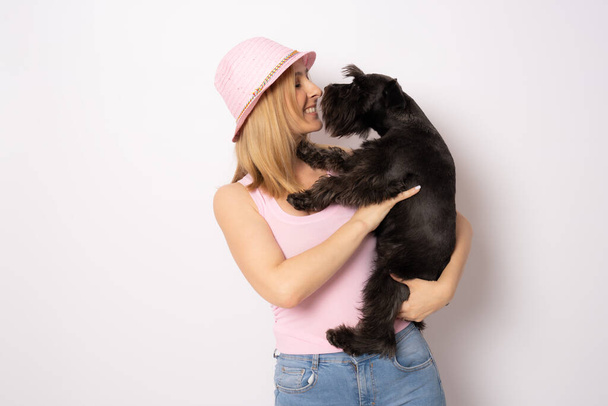 Nette junge Frau umarmt ihren Welpen Schnauzer Hund. Liebe zwischen Herrchen und Hund. Vereinzelt auf weißem Hintergrund. Studioporträt. - Foto, Bild