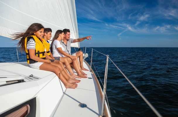 Young Latin American parents with children in lifejackets enjoying fun adventures on family sailing vacation on luxury yacht - Fotó, kép