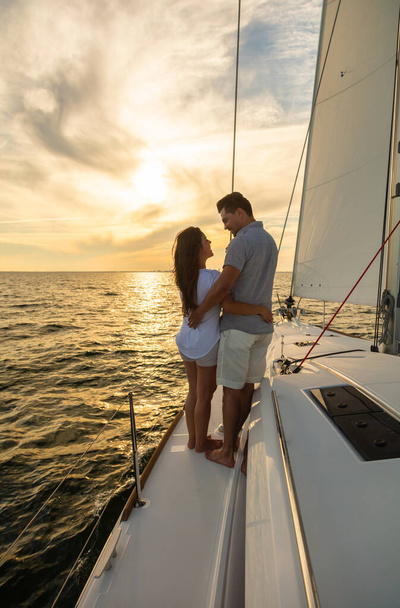 Loving young Hispanic couple travelling together on luxury vacation sailing the ocean on private yacht at sunrise - 写真・画像