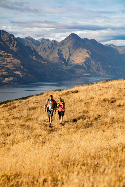 Jong Nieuw-Zeeland avontuur reizen toeristisch paar met rugzakken trekking The Remarkables terwijl op vakantie in de buurt van Lake Wakatipu Otago - Foto, afbeelding