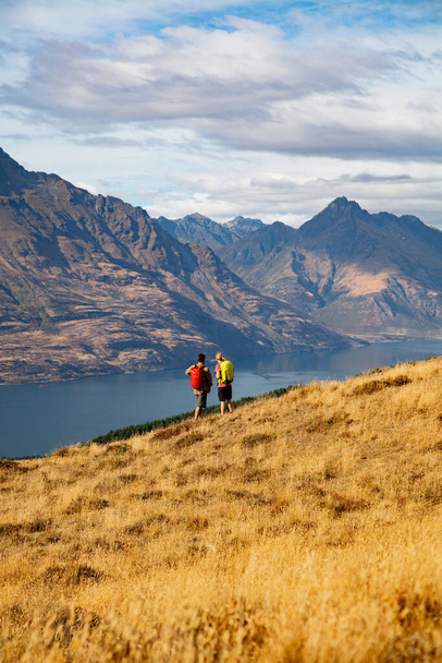Lake Wakatipu passen extreme Kaukasische mannelijke en vrouwelijke jonge wandelen paar wandelen berg reizen parcours buiten De opmerkelijke Otago Nieuw-Zeeland - Foto, afbeelding