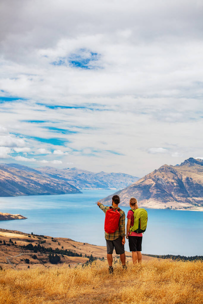 The Remarkables young Caucasian couple with backpacks extreme trekking to keep fit outdoors near Lake Wakatipu Otago New Zealand - Photo, Image