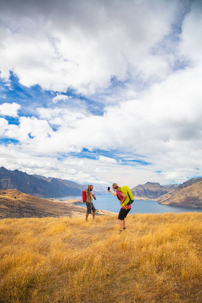 Nieuw-Zeelandse succesvolle jonge Kaukasische echtpaar het nemen van een reisfoto in de buurt van Lake Wakatipu Queenstown tijdens een trekking avontuur vakantie buiten The Remarkables Otago - Foto, afbeelding