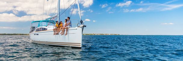Panorama of Latin American mother and father with young children enjoying carefree travels on luxury family vacation sailing private yacht - Photo, image