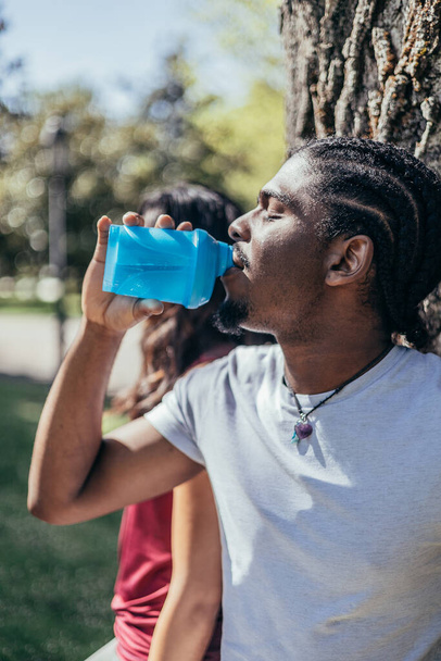 african american athlete boy drinks water from a bottle in a park. - Fotografie, Obrázek