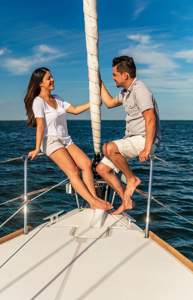 Successful young Latino couple relaxing outdoors together on Summer vacation sailing the ocean on luxury private yacht - Photo, Image