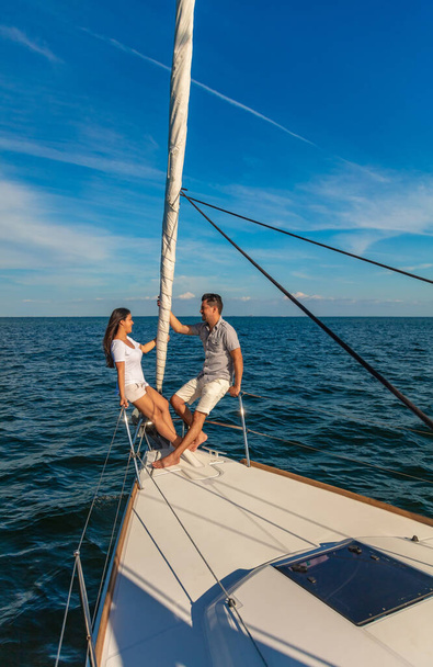 Successful Latin American couple enjoying leisure time together sailing the ocean and relaxing outdoors on luxury private yacht - Fotografie, Obrázek
