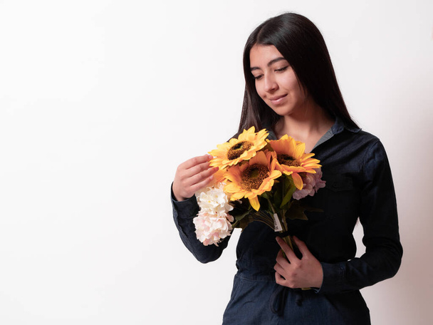 close up Hispanic woman isolated on white background holding in her hands a bouquet of sunflowers looking tenderly, gift concept for a woman, mother's day - Fotoğraf, Görsel