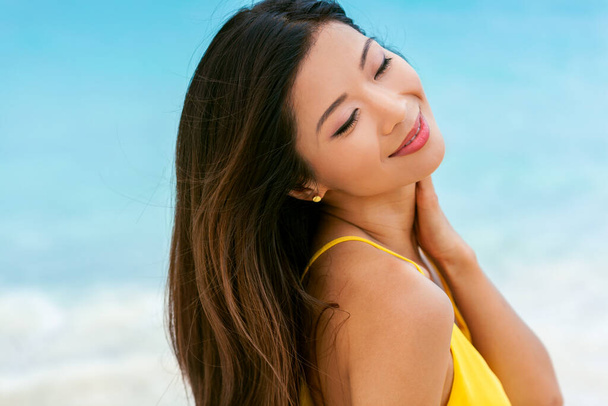 Menina asiática atraente em amarelo ao ar livre sorrindo alegremente desfrutando de férias relaxantes na praia no resort ilha tropical Bahamas - Foto, Imagem