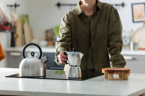 Woman make a coffee in moka pot in kitchen - Foto, afbeelding