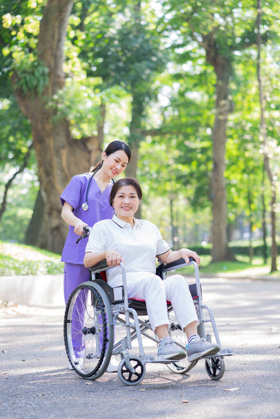 Azjatka pielęgniarka zajmująca się pacjentką w średnim wieku w parku - Zdjęcie, obraz