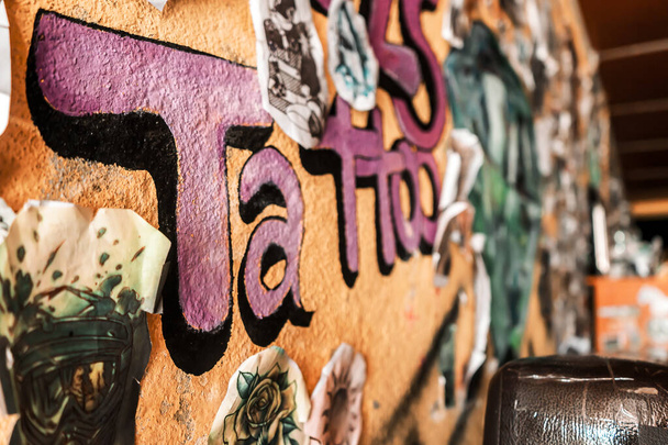 Τατουάζ τοίχο στούντιο σε ένα σαλόνι της Λατινικής Αμερικής με σκίτσα κρέμονται στον τοίχο και ένα γκράφιτι ζωγραφισμένα - Φωτογραφία, εικόνα