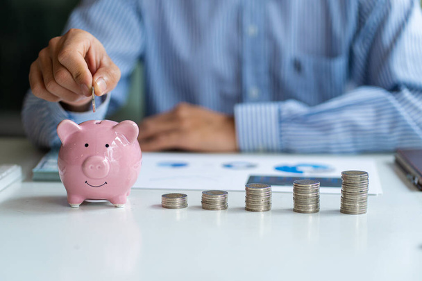 Savings accountant holding a coin in a pink pig piggy bank Finance and Accounting Concepts - Foto, Bild