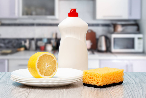 Bouteilles de liquide vaisselle, éponge, assiettes et citron. - Photo, image