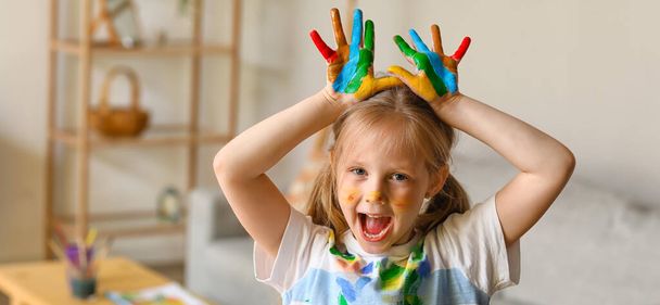 Funny little girl with palms in paint at home - Foto, imagen