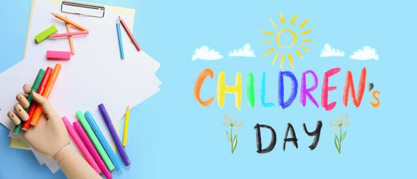 Hojas de papel en blanco con mano de madera, rotuladores, lápices y gomas de borrar sobre fondo azul. Día de los Niños - Foto, imagen