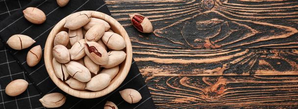 Bowl with tasty pecan nuts on wooden background with space for text - Foto, immagini