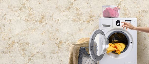 Hand taking clothes out of washing machine on color background. Banner for design - Фото, изображение