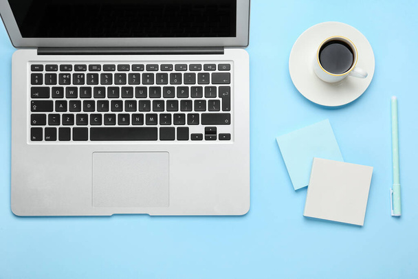 Λευκά αυτοκόλλητα σημειώματα, στυλό, laptop και φλιτζάνι καφέ σε μπλε φόντο - Φωτογραφία, εικόνα