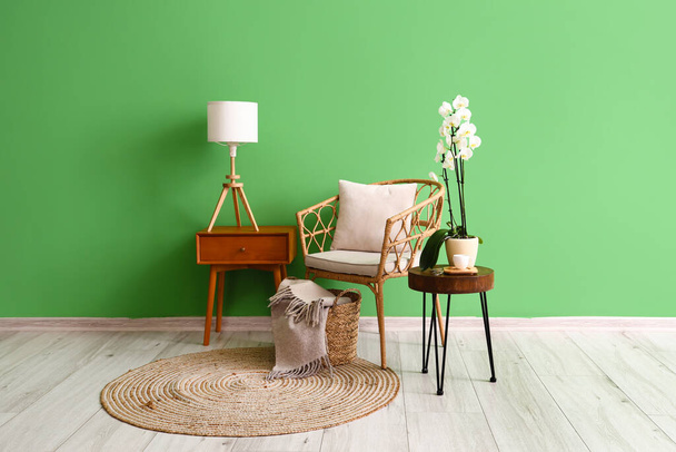 Ψάθινη καρέκλα και τραπέζια κοντά σε πράσινο τοίχο στο εσωτερικό του δωματίου - Φωτογραφία, εικόνα