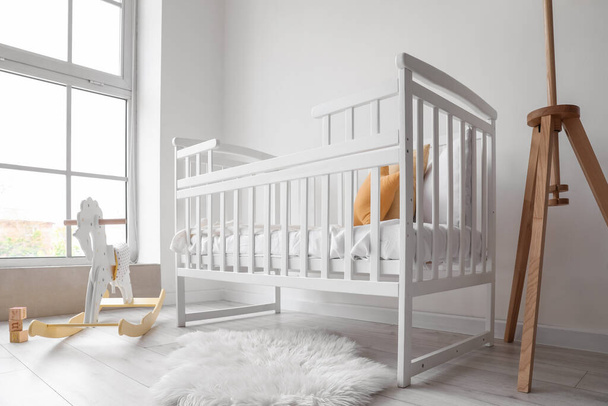 Baby crib with rocking horse and cubes near light wall - Photo, Image