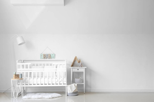 Wnętrze lekkiego żłobka z łóżeczkiem niemowlęcym, lampą i stołami - Zdjęcie, obraz