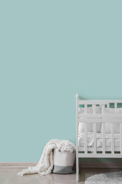 Παιδική κούνια και καλάθι με κουβέρτα κοντά σε πράσινο τοίχο - Φωτογραφία, εικόνα