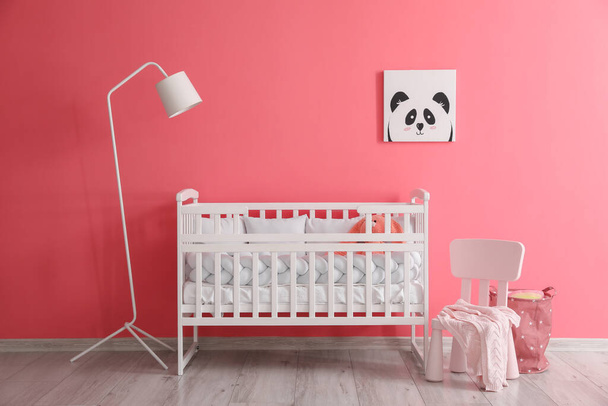 Interior of stylish nursery with baby crib, lamp and chair - Foto, Bild