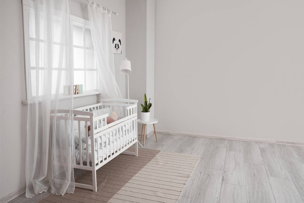 Interior of light nursery with baby crib, lamp and window - Photo, Image