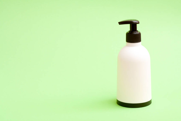 Bouteille de savon en plastique blanc avec haut et bas blat sur fond vert avec espace de collage gratuit pour le texte. - Photo, image