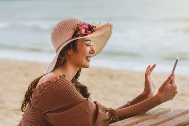 Lomalla Pattaya rannalla, aasialainen onnellinen nuori kaunis nainen mekko kangas video soittaa ystävien kanssa vaaleanpunainen tuoli ylellisessä kahvilassa. - Valokuva, kuva