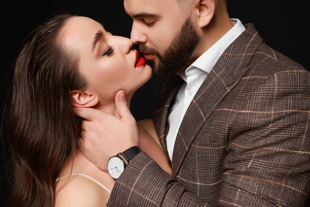 Handsome bearded man with sexy lady on black background, closeup - Photo, image