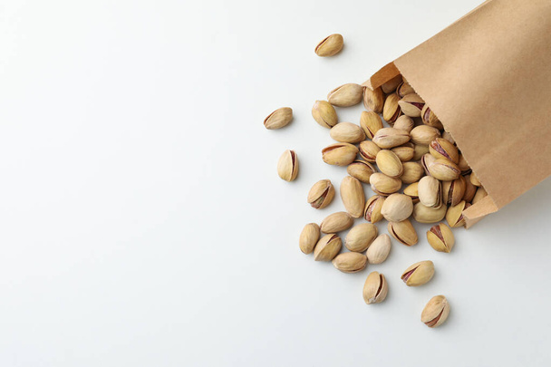 Overturned paper bag with pistachio nuts on white background, flat lay. Space for text - Foto, immagini