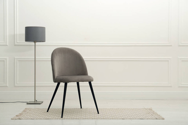 Modern beige chair and floor lamp near white wall indoors. Space for text - Foto, Imagem