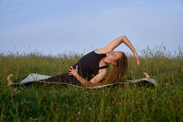 Bloody smiling girl doing side banding on yoga mat. - Foto, Bild