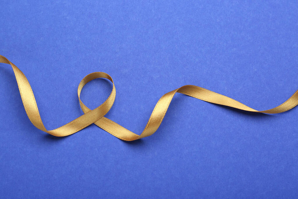 Beautiful golden ribbon on blue background, top view - Photo, Image