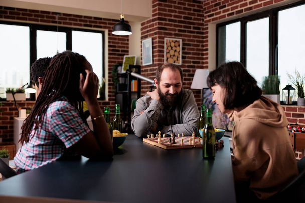 Multi-etnische groep vrienden die thuis schaakbordspel spelen - Foto, afbeelding