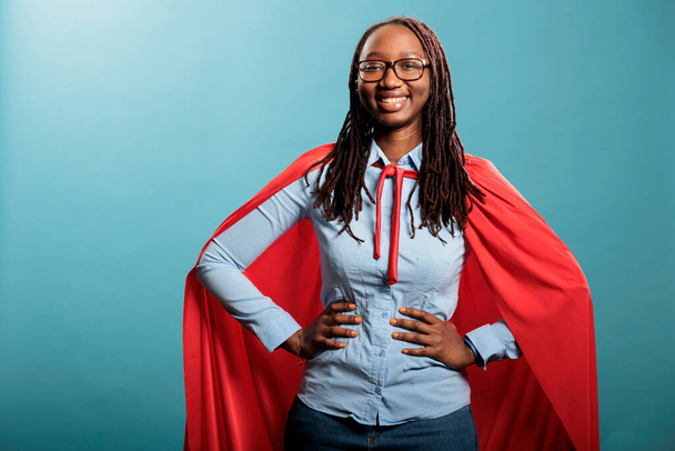 Proud superhero woman with superpower abilities wearing mighty hero cloak while smiling confident at camera. - Photo, image