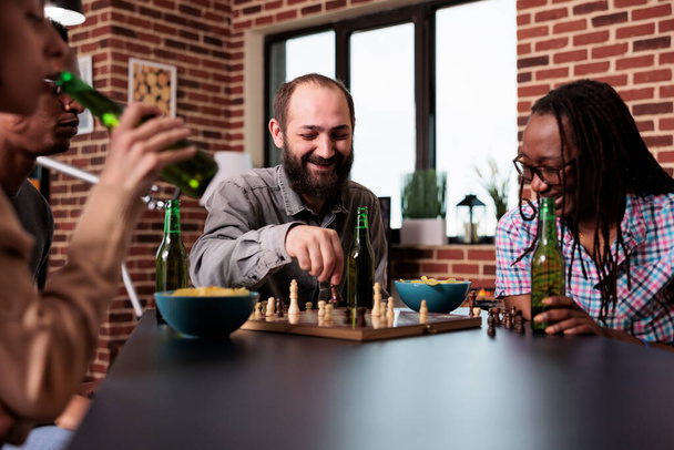 Lachen diverse vrienden zitten samen thuis tijdens het spelen van strategie bordspellen. - Foto, afbeelding