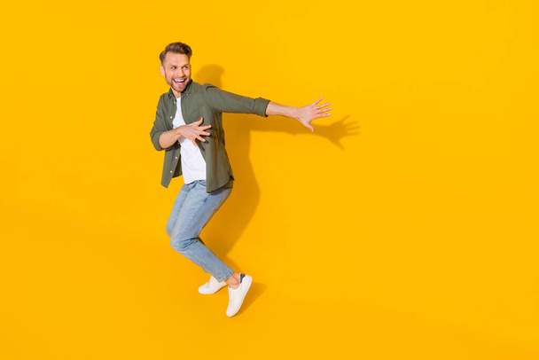 Full length body size view of attractive cheerful crazy guy dancing having fun isolated over bright yellow color background - Foto, afbeelding