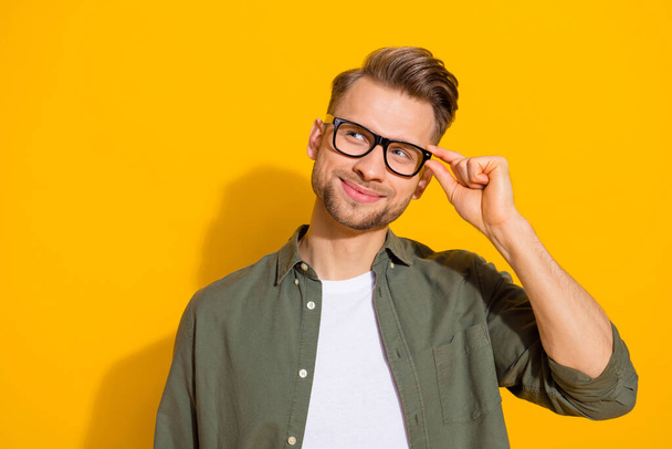 Portrait of attractive cheerful pensive guy touching specs making decision copy space isolated over bright yellow color background - Photo, Image